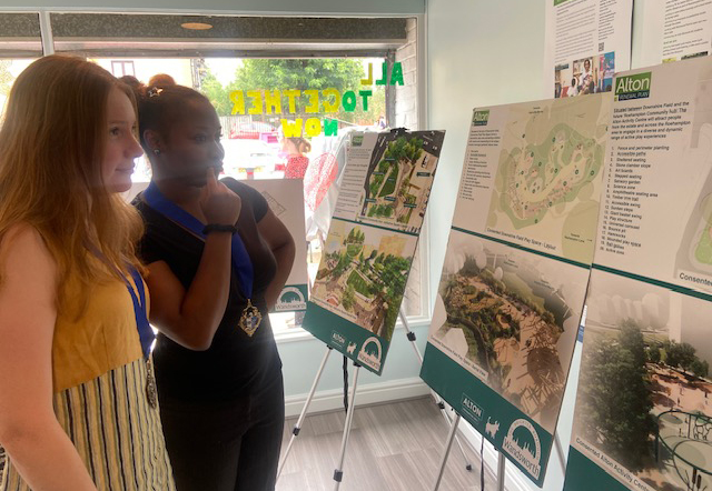 Two people are pictured studying exhibition boards which introduce the Alton Renewal plans.