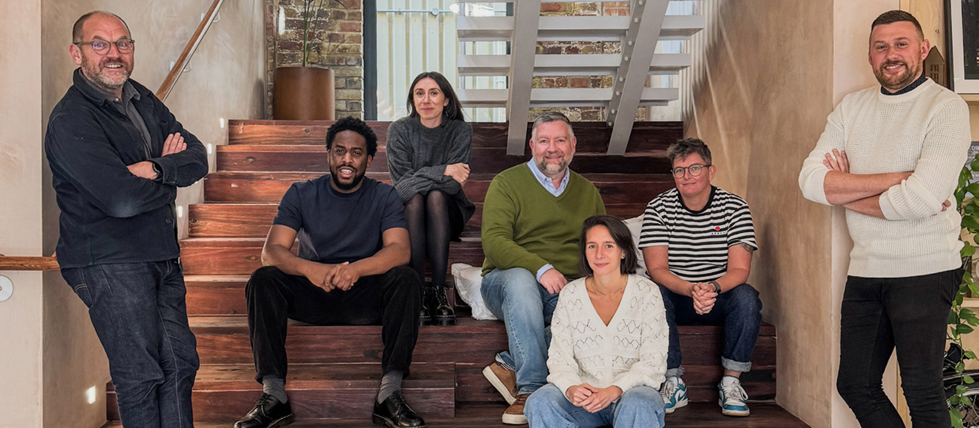 The Alton Renewal Plan design team members are pictured sitting and standing on a staircase. There are seven people in the picture.