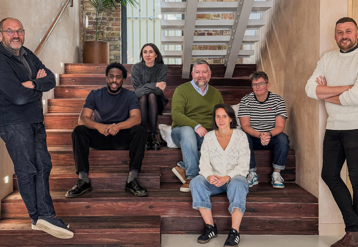 The Alton Renewal Plan design team members are pictured sitting and standing on a staircase. There are seven people in the picture.