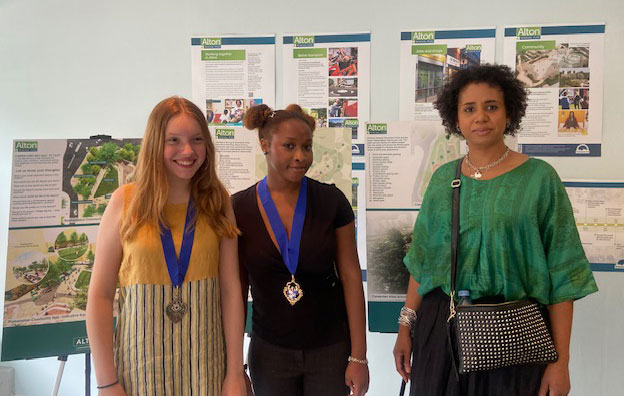 Three people are pictured standing in front of Alton Renewal information boards